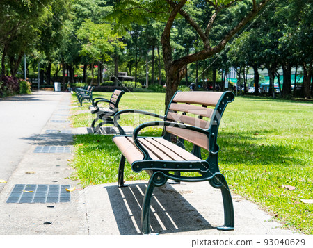 Summer park, green lanes, walking paths, park benches under trees, sunny days. 93040629