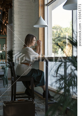 Portrait of mature woman in cafe. Middle aged woman sits at table in cozy cafe near large window. Vertical frame. Portrait of mature woman in cafe. Middle aged woman sits at table in cozy cafe near large window. Vertical frame. 93041771
