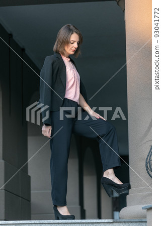 Stylish woman in trousers and jacket. Middle aged business woman rests on the street Stylish woman in trousers and jacket. Middle aged business woman rests on the street 93041772