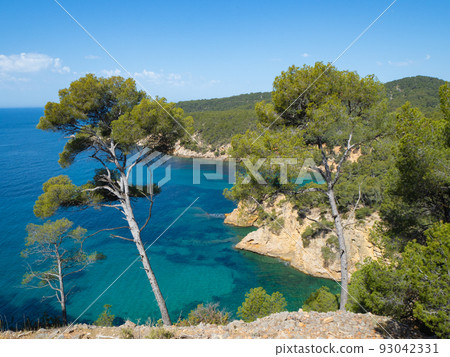 Bandol, France - May 16th 2022: Small rocky bays under pine forests in front of the deep blue sea. Bandol, France - May 16th 2022: Small rocky bays under pine forests in front of the deep blue sea. 93042331