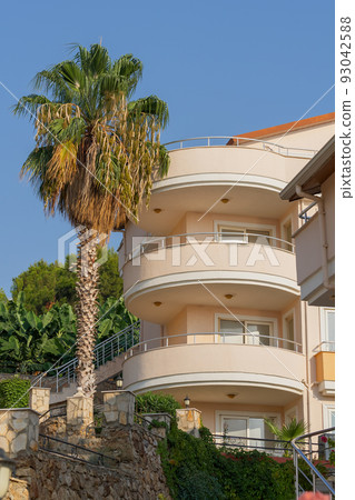 Part of the southern residential building. Growing palm tree next to the house. Part of the southern residential building. Growing palm tree next to the house. 93042588