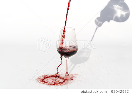 Sommelier pours red wine from decanter to wineglass on white background. spilling red wine past the glass on a white table. Sommelier pours red wine from decanter to wineglass on white background. spilling red wine past the glass on a white table. 93042922
