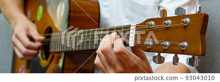 Young boy playing guitar. Close-up of man hand playing classic guitar. teenager learning playing guitar. Banner or panoramic shot. 93043010