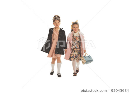 Studio shot of little happy girls in retro style outfit, fashion of 70s, 80s years isolated on white background. Concept of art, friendship, hope, youth Studio shot of little happy girls in retro style outfit, fashion of 70s, 80s years isolated on white background. Concept of art, friendship, hope, youth 93045684