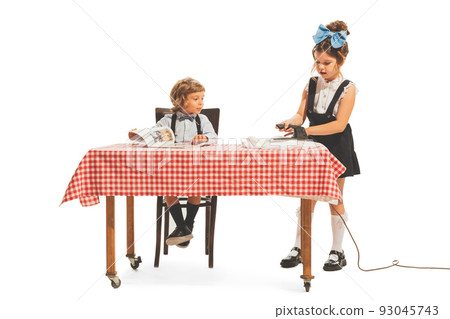Creative composition with two little kids, boy and girl in retro american style outfits like family couple isolated on white background. Comparison concept Creative composition with two little kids, boy and girl in retro american style outfits like family couple isolated on white background. Comparison concept 93045743