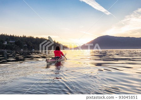 Adventurous Woman on Sea Kayak paddling in the Pacific Ocean. Sunny Summer Sunset Adventurous Woman on Sea Kayak paddling in the Pacific Ocean. Sunny Summer Sunset 93045851