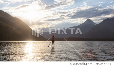 Adventurous Woman Paddle Boarding in a Lake around Canadian Mountain Landscape 93045885