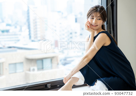 Young woman sitting by the window and relaxing 93047732