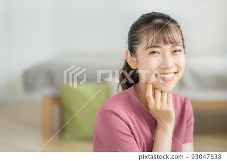 在客廳裡微笑的年輕女人 在客廳裡微笑的年輕女人 93047838