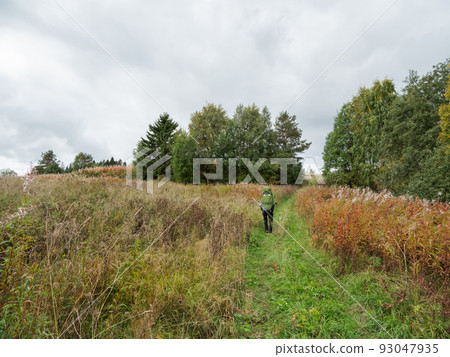 Backpacker goes on country road. Man with touristic rucksack is hiking in summer or autumn season. Active lifestyle. Outdoor leisure activity. Backpacker goes on country road. Man with touristic rucksack is hiking in summer or autumn season. Active lifestyle. Outdoor leisure activity. 93047935