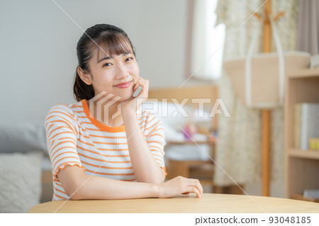 坐在客廳裡微笑的年輕女人 坐在客廳裡微笑的年輕女人 93048185