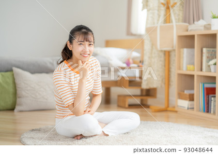 Young woman sitting on the floor in the living room and smiling 93048644