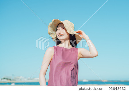A young woman in a dress staring at the sea 93048682