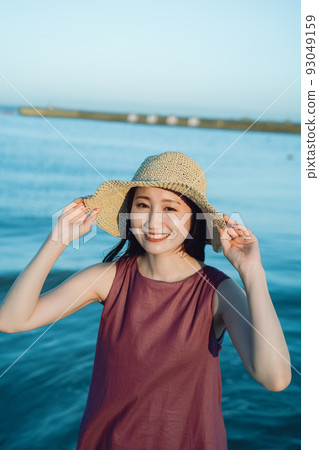 Young woman in straw hat playing on the beach 93049159