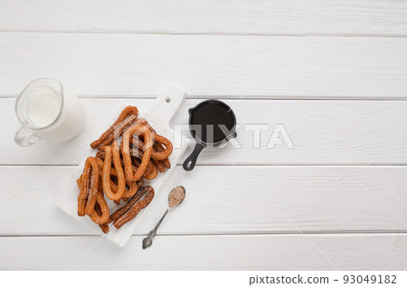 Homemade churros with chocolate on a white wooden background. Homemade churros with chocolate on a white wooden background. 93049182