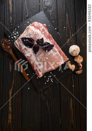 A large piece of pork loin with basil on a rustic dark background. A large piece of pork loin with basil on a rustic dark background. 93049283