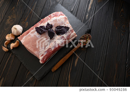 A large piece of pork loin with basil on a rustic dark background. A large piece of pork loin with basil on a rustic dark background. 93049286
