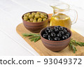 Black and green olives on a white wooden background. 93049372