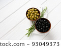 Black and green olives on a white wooden background. 93049373