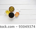 Black and green olives on a white wooden background. 93049374