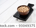 Uncooked chickpeas in bowl on white wooden background 93049375