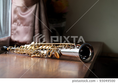 Soprano Saxophone on the Wood Table in the Morning, Selective Focus Silver Plated Golden Key Saxophone Picture. Soprano Saxophone on the Wood Table in the Morning, Selective Focus Silver Plated Golden Key Saxophone Picture. 93049500