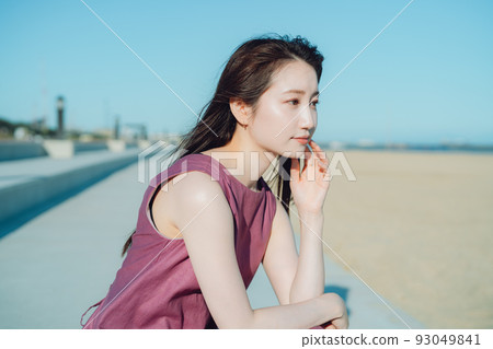 一個穿著連衣裙的年輕女子望著大海 93049841