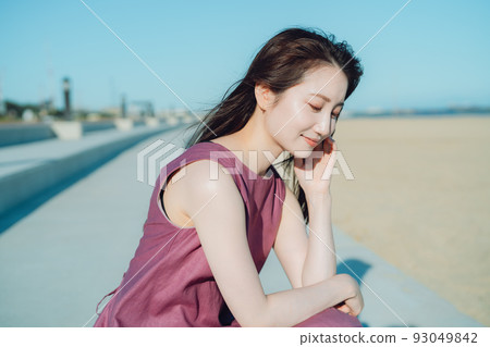 一個穿著連衣裙的年輕女子望著大海 93049842