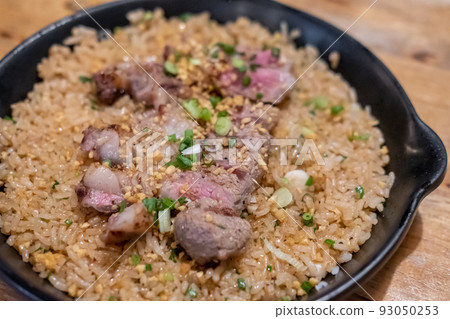 Beef with garlic fried rice, a Japanese dish consisting of a bowl of rice topped with rare beef served on a black pan Beef with garlic fried rice, a Japanese dish consisting of a bowl of rice topped with rare beef served on a black pan 93050253