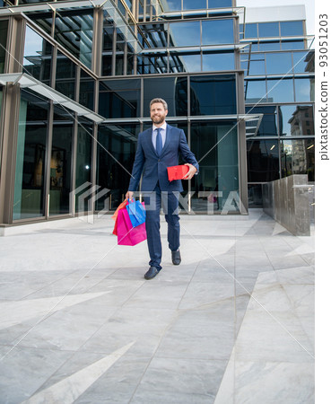 cheerful business man walk outdoor with shopping bags for holiday, full length, birthday. 93051203