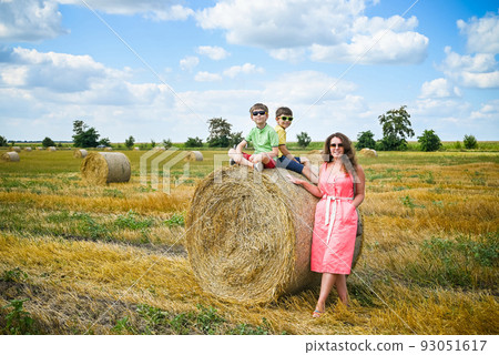 Happy family in a wheat field. Mother and two sibling brother bo Happy family in a wheat field. Mother and two sibling brother bo 93051617