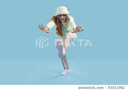 Cheerful crazy and strange young woman having fun on light blue background in studio. Cheerful crazy and strange young woman having fun on light blue background in studio. 93052962