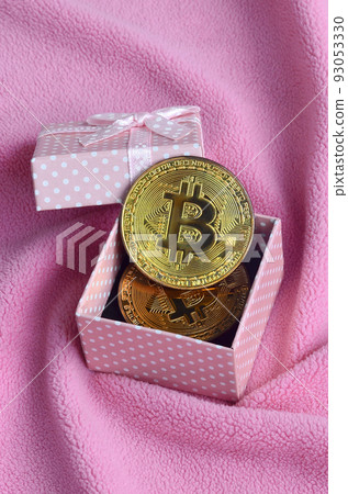 The golden bitcoin lies in a small pink gift box with a small bow on a blanket made of soft and fluffy light pink fleece fabric with a large number of relief folds The golden bitcoin lies in a small pink gift box with a small bow on a blanket made of soft and fluffy light pink fleece fabric with a large number of relief folds 93053330