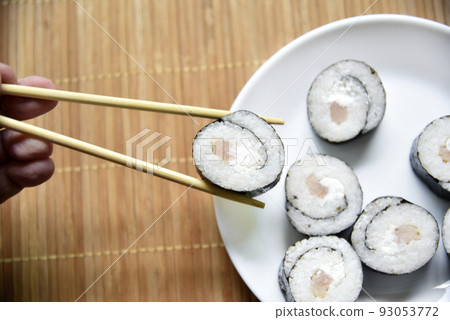 Taken with chopsticks sushi with tuna for eating. Delicious fish roll. Rice sushi roll on a mat. Taken with chopsticks sushi with tuna for eating. Delicious fish roll. Rice sushi roll on a mat. 93053772
