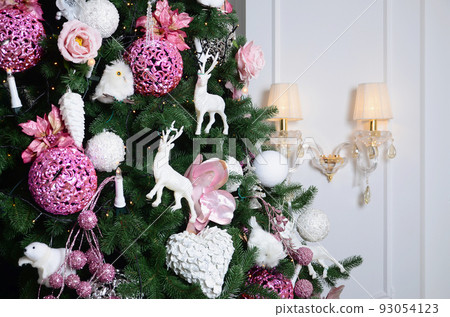 Decorating Christmas tree close up. Decoration bulb, fir tree, pink x-mas toys and lights. Use for Christmas and New years celebration background Decorating Christmas tree close up. Decoration bulb, fir tree, pink x-mas toys and lights. Use for Christmas and New years celebration background 93054123