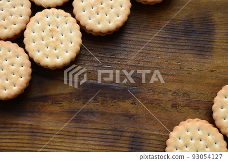 A round sandwich cookie with coconut filling lies in large quantities on a brown wooden surface. Photo of edible treats on a wooden background with copy space A round sandwich cookie with coconut filling lies in large quantities on a brown wooden surface. Photo of edible treats on a wooden background with copy space 93054127