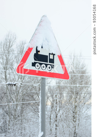Railway crossing without barrier. A road sign depicting an old black locomotive, located in a red triangle Railway crossing without barrier. A road sign depicting an old black locomotive, located in a red triangle 93054168