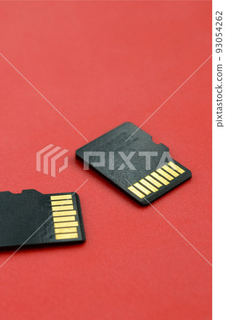 Two small micro SD memory cards lie on a red background. A small and compact data and information store 93054262
