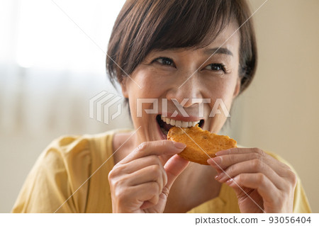 Middle woman eating rice cracker 93056404
