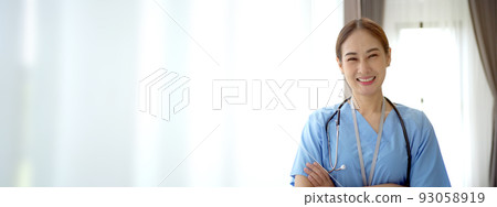 Portrait of cheerful Asian female doctor smiling and arms crossing to camera, attractive - good looking woman doctor in hospital with copyspace. 93058919