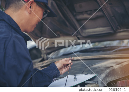 Car Mechanic man hand checking dipstick engine oil car mechanical on site service. Close up hand man check engine oil level Locate dipstick, wipe clean, check dipstick level before fill up engine oil 93059641