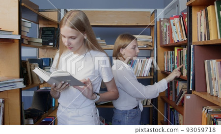 4K. Young female students choose a book to read in the college library. 4K. Young female students choose a book to read in the college library. 93059718