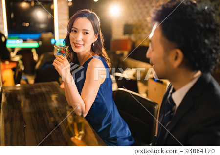 A beautiful woman drinking with a bearded man in his 40s 93064120