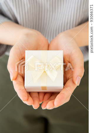 Young woman with a small gift box of presents Young woman with a small gift box of presents 93066371