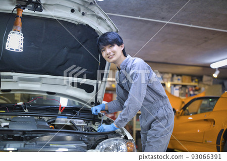 An auto mechanic inspecting the inside of the hood 93066391