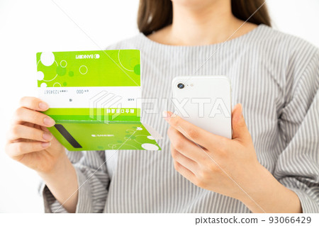 Young woman with passbook and smartphone 93066429
