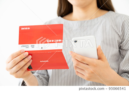 Young woman with passbook and smartphone 93066541