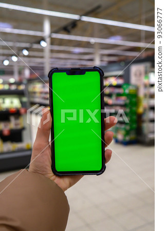 Chroma key. Close up of woman hand holds smart phone vertical with green screen at shopping mall store. Shopping center. Department store. Shopping online. Gadgets template 93066777