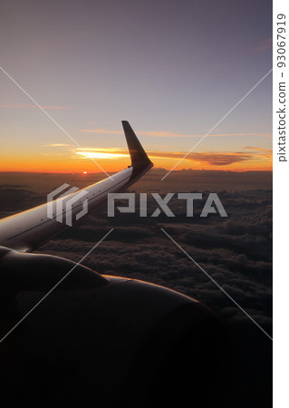 從飛機的窗戶和發光的飛機機翼看到的地平線上的日落 從飛機的窗戶和發光的飛機機翼看到的地平線上的日落 93067919