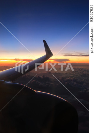 Sunset sky seen from the window of an airplane and the figure of a shining airplane 93067925